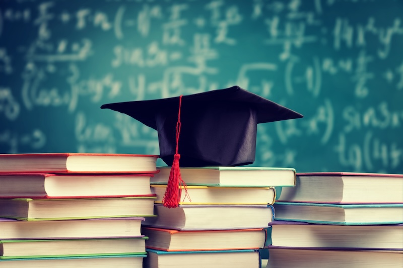 Staplade böcker och studentmössa